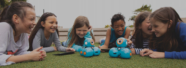 Tween girls playing outside with Dash robots